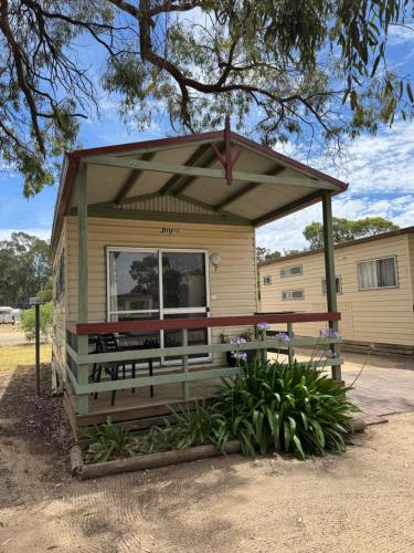 a tiny house with a porch and a large window at Hay Caravan Park in Hay
