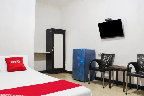 a room with a bed and two chairs and a tv at Hotel O We Bro Kost in Kupang