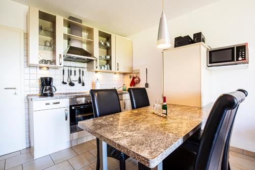 a kitchen with a table and some black chairs at Südblick 2Whg 6 in Werdum
