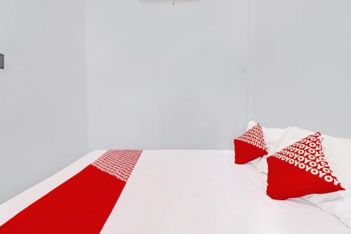 a bed with red and white pillows on it at Hotel O Gala Residence in Jambi