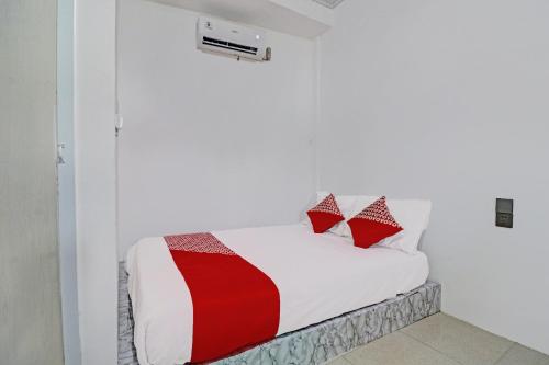 a white room with a bed with red and white pillows at Hotel O Gala Residence in Jambi