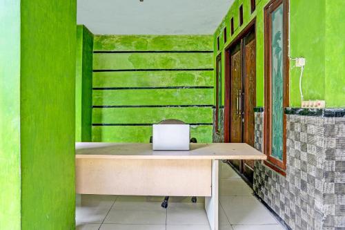 a desk in a room with green walls at Hotel O Fun Guesthouse Syariah in Mojokerto