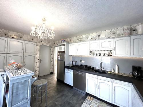 une cuisine avec des armoires blanches et un lustre dans l'établissement Maison 5 pièces 8 personnes - Vue mer - LOEVA, à Ploemeur