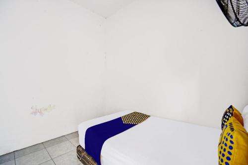 a bed in a room with a white wall at Hotel O Fun Guesthouse Syariah in Mojokerto
