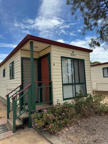 a tiny house with a red door and a porch at Hay Caravan Park in Hay
