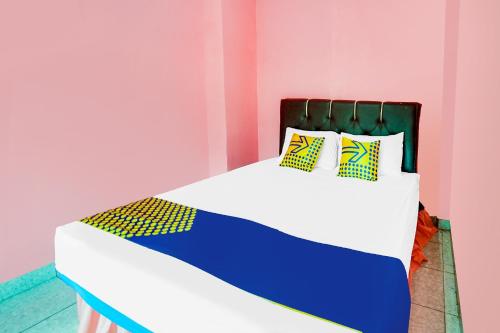 a bed in a pink room with yellow and blue pillows at OYO Life 92046 Garuda Residence in Palembang