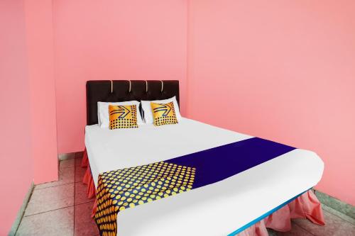 a bed in a room with a pink wall at OYO Life 92046 Garuda Residence in Palembang