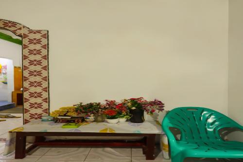 a table with flowers and a green chair at Hotel O Homestay Bude Sri in Batam Center
