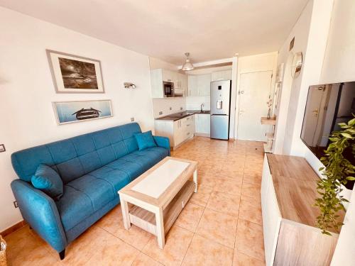 a living room with a blue couch and a kitchen at Sunset Taurito in Taurito