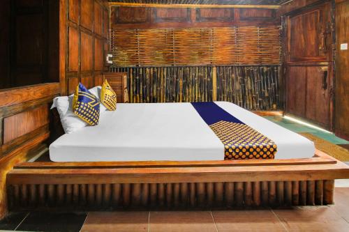 a large bed in a room with wooden walls at OYO 92083 Lailik Gilang Guesthouse in Watukarung