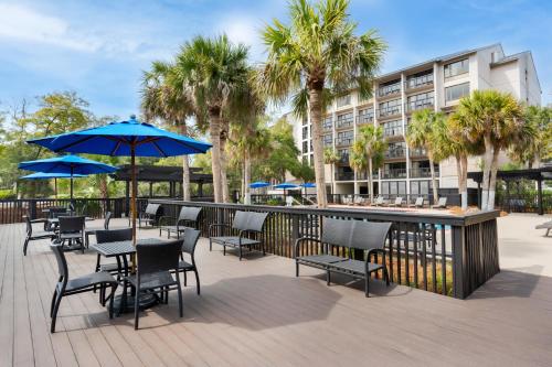 a patio with tables and chairs and a bar with blue umbrellas at Holiday Inn Express Hilton Head Island by IHG in Hilton Head Island
