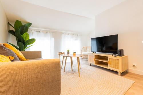 un salon avec un canapé, une télévision et une table dans l'établissement Duplex Confortable en Centre avec 2 Chambres, à Châlons-en-Champagne