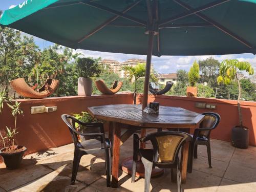 a table and chairs under an umbrella on a patio at Khweza Bed and Breakfast in Nairobi