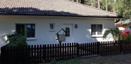a white house with a fence in front of it at Ferienhaus Fichtenwalde in Beelitz