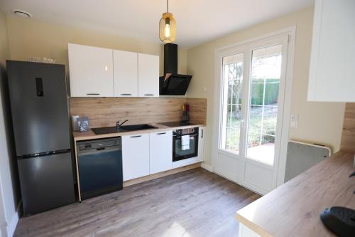 a kitchen with white cabinets and a black refrigerator at La villa Fontaine in Moussy