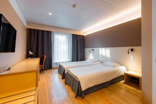 a hotel room with two beds and a flat screen tv at Saaremaa Rannahotell ' Beach Hotel in Mändjala
