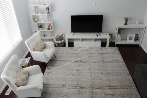 a living room with white furniture and a flat screen tv at Spacious 4BR-4BA House for Large Families & Group in Stonebridge in Saskatoon