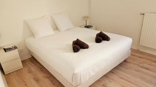 - un lit blanc avec 2 oreillers bruns dans l'établissement Paul Eluard - Maison au calme parking centre Tours, à Tours