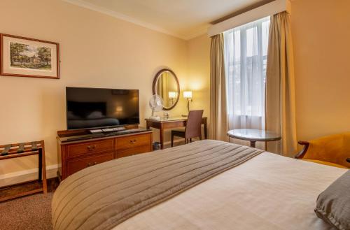 a hotel room with a bed and a flat screen tv at Hollins Hall Hotel, Golf & Country Club in Bradford