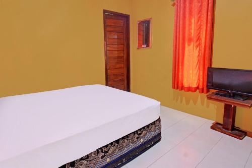 a bedroom with a bed and a flat screen tv at Hotel O Ujung Samalas HomestayNearLapangan Sembalun Bumbung in Labuan Lombok