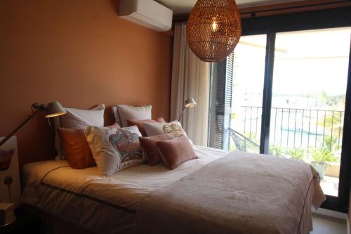 une chambre avec un lit avec des oreillers et une fenêtre dans l'établissement Brigantine309 - Golfe de St-Tropez - Bel appartement avec vue port, à Cogolin