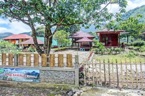 a fence in front of a house with a tree at Hotel O Ujung Samalas HomestayNearLapangan Sembalun Bumbung in Labuan Lombok