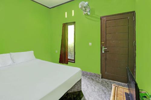 Un dormitorio verde con una cama y una puerta. en Hotel O Ashooy HomestayNearWisata Desa sedau, en Lombok