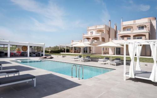 a swimming pool with chairs and a building at Ema's Guest House in Porto Rafti