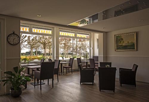 a dining room with tables and chairs and a clock at Hotel Sonnenklause in Travemünde