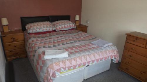 a bedroom with a bed and a wooden dresser at Two bedroom timber lodge Avonvale Holiday Lodges in Evesham