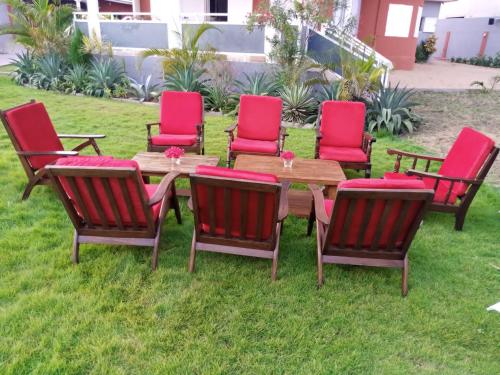 a group of red chairs around a wooden table at Maison Stella Lome in Lomé