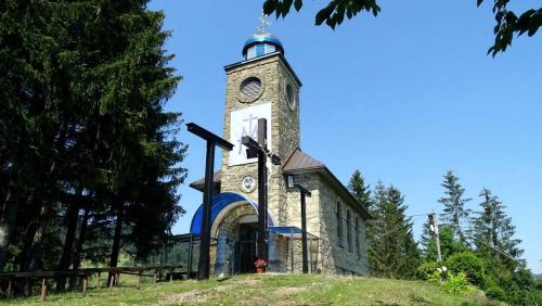 an old church with a clock tower on a hill at Vila LiMi in Oščadnica