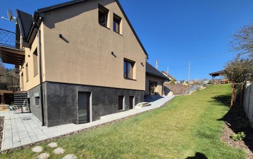 a house with a grassy yard next to a building at Vila LiMi in Oščadnica