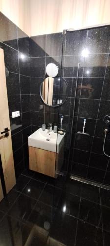 a black tiled bathroom with a sink and a shower at Vila LiMi in Oščadnica