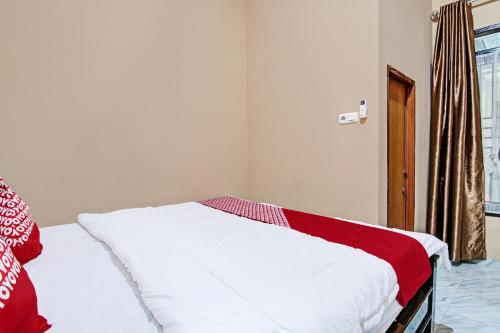 a bedroom with a white bed with a red blanket at Hotel O Sandira Syariah in Dumai