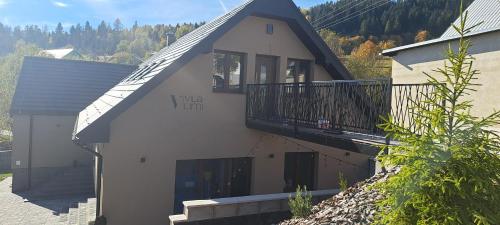 a house with a balcony on the side of it at Vila LiMi in Oščadnica