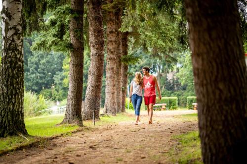 a man and woman walking down a path in a park at Ferienhaus am See in Sondershausen