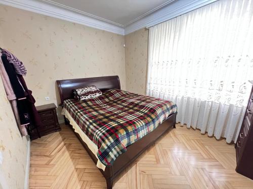 a bedroom with a bed with a blanket and a window at Cozy 5BD House With Frontyard in Tbilisi City