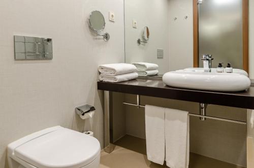 a bathroom with a sink and a toilet and a mirror at TURIM Av. Liberdade Hotel in Lisbon