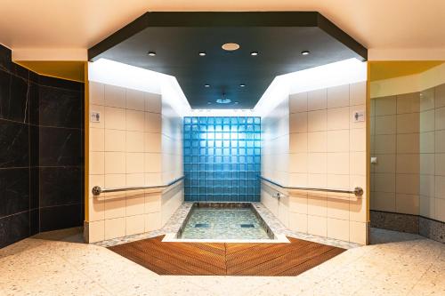a bathroom with a shower with a blue tile wall at Saaremaa Rannahotell ' Beach Hotel in Mändjala