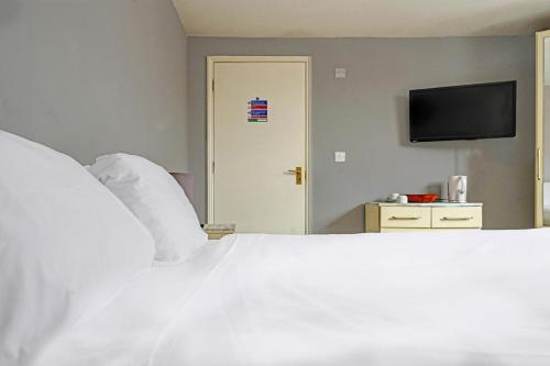 a bedroom with a white bed and a flat screen tv at The Billingford Horseshoes in Scole