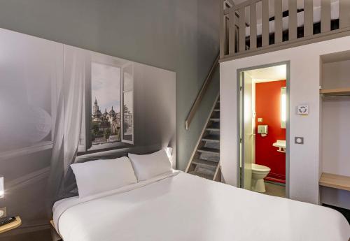 a bedroom with a white bed and a staircase at B&B HOTEL Périgueux Boulazac in Boulazac