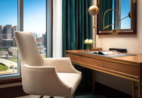 a desk with a chair and a desk with a window at Blossom Hotel Houston, Curio Collection by Hilton in Houston