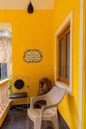 a yellow room with a chair and a window at GOAROUND- Portuguese Villa at Anjuna Beach by Goaround Homes in Anjuna