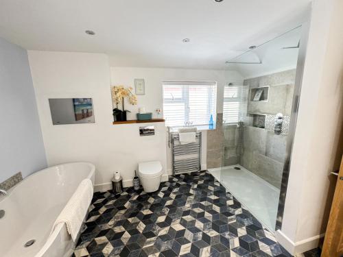 a bathroom with a tub and a toilet and a shower at Seasons in Weymouth