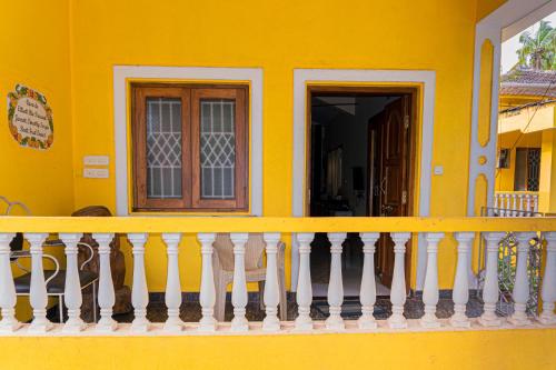 a yellow house with a white railing on a balcony at GOAROUND- Portuguese Villa at Anjuna Beach by Goaround Homes in Anjuna
