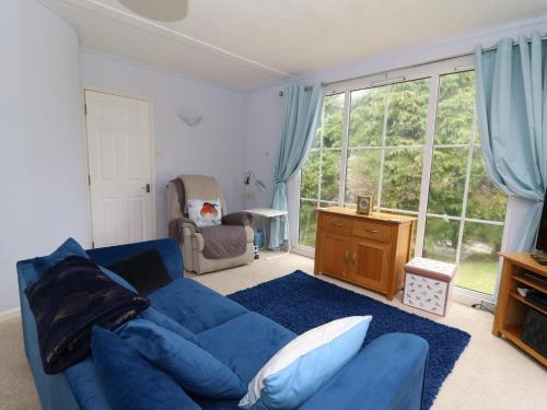 a living room with a blue couch and a large window at Nanny Jill's Cabin in Penrydd