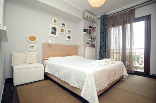 a white bedroom with a bed and a chair at Artistic elegant home in Afitos