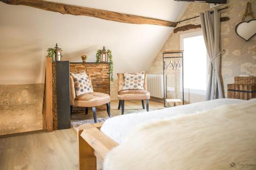 a bedroom with two chairs and a bed at La Ferme de Labbeville in Labbeville
