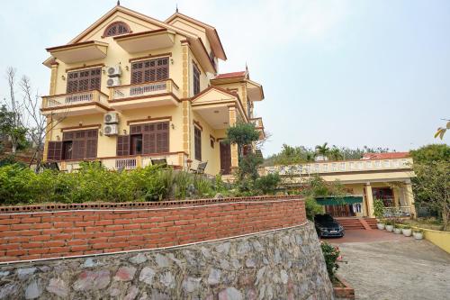 a large yellow house with a brick wall at Kim's Family Hotel in Ha Long